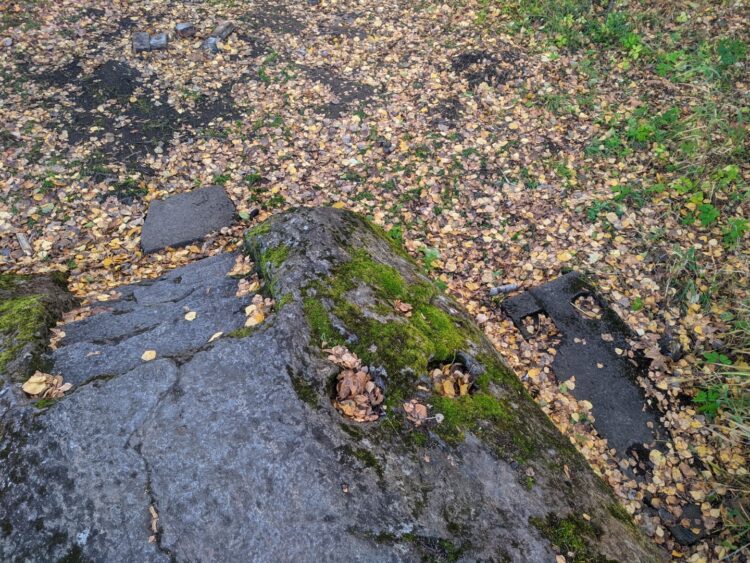 Валун с вырубленными ступеньками и каменной скамьёй позади павильона. 